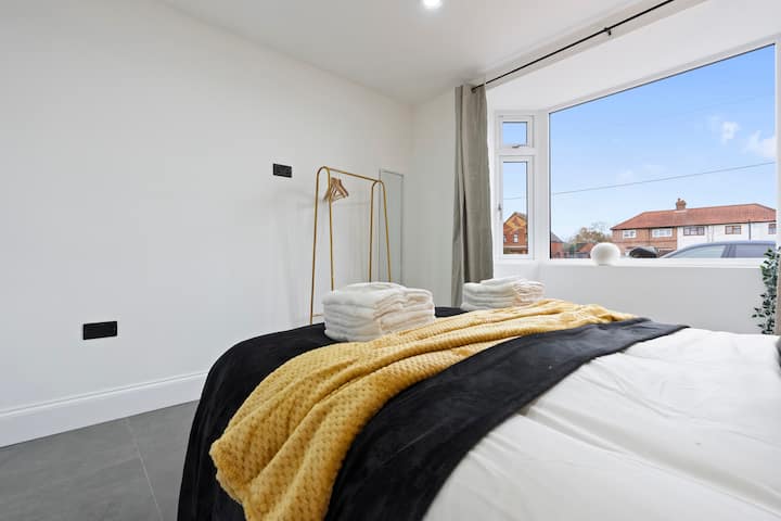 Spavaća soba s bračnim krevetom, prozorom i ormarićem za odlaganje.