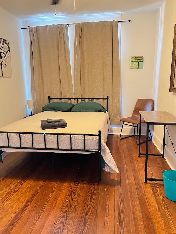 Camera da letto luminosa e pulita con zona lavoro, cassettiera e atmosfera rilassante.