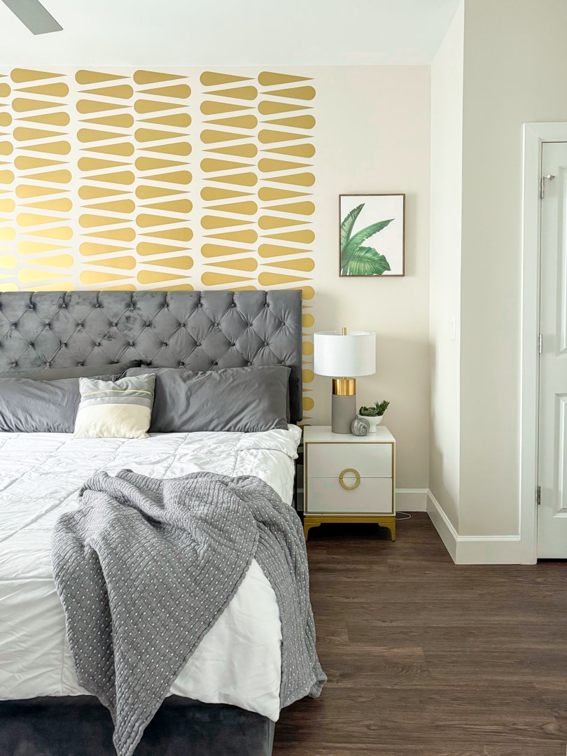 ห้องนอนหรูหราพร้อมหัวเตียงสีเทาผ้าทอการตกแต่งด้วยสีทองและผนังที่สะดุดตา ผ่อนคลายบนเตียงขนาดคิงไซส์ด้วยผ้าปูที่นอนระดับพรีเมียม