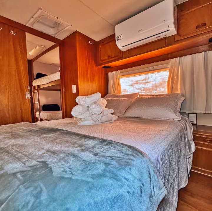 Quarto com cama queen, beliche, ar-condicionado, blackout nas cortinas, local para guardar as roupas e roupa de cama.