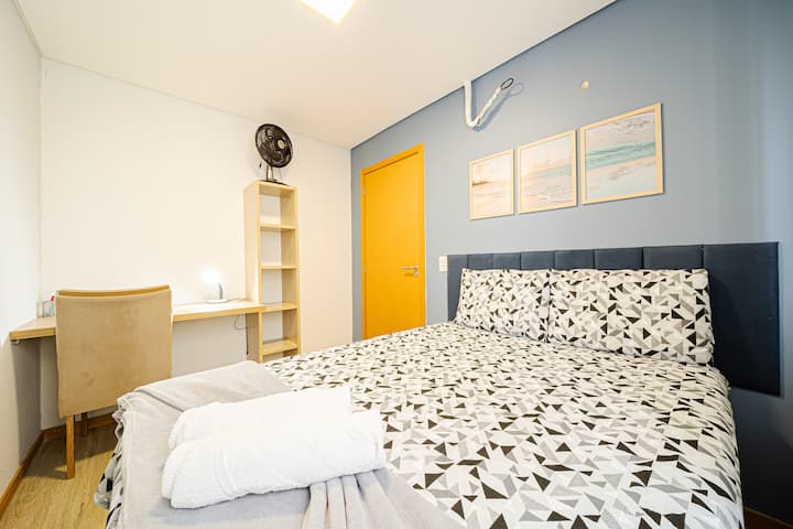 ห้องพักพร้อมเตียงคู่โต๊ะเคบินพร้อมเต้ารับใกล้เคียงโต๊ะเขียนหนังสือและพัดลม ห้องนี้ยังมีเครื่องปรับอากาศ อากาศของห้องสามารถใช้กับประตูที่เปิดอยู่ซึ่งตอบสนองในวันที่อากาศร้อนมาก Dias amenos nção Precisa.