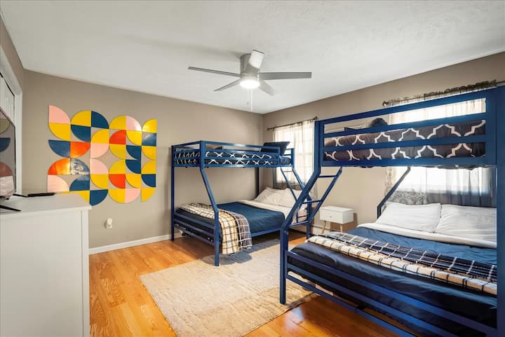 Тази оживена спалня разполага с два комплекта двуетажни легла - два единични и два пълноразмерни матрака, в които удобно могат да се настанят до шест души. Игривото геометрично стенно изкуство добавя забавно, модерно докосване, създавайки оживено, приветливо пространство за семейни или групови престои.