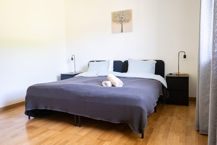 [Dormitorio 2] Armario con perchas y cajones, silla, 2 camas para 1 persona y enchufe junto a cada cama. A tu izquierda tienes un gran ventanal con vistas y cortinas y persianas . 