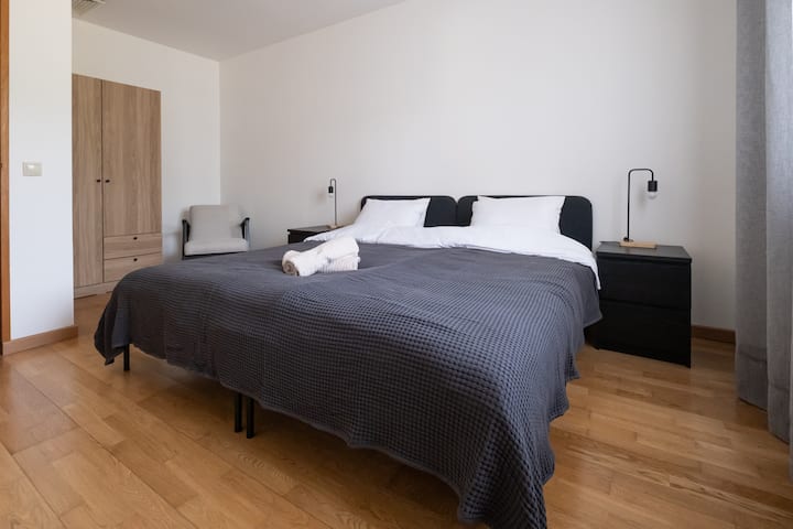 [Dormitorio 4] Armario con perchas y cajones, silla, 2 camas para 1 persona y enchufe junto a cada cama. A tu izquierda tienes un gran ventanal con vistas y cortinas y persianas . 