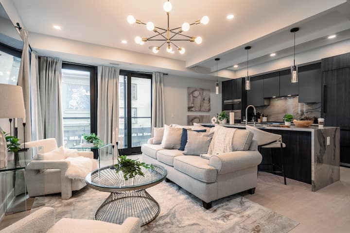 Útulná obývacia izba s veľkými oknami ponúka výhľad na ulicu, pohodlnú pohovku a štýlovú výzdobu.