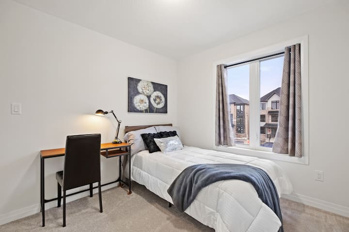 ห้องนอนสว่างและใช้งานได้ดีพร้อมเตียงแฝดและพื้นที่ทำงานโดยเฉพาะ