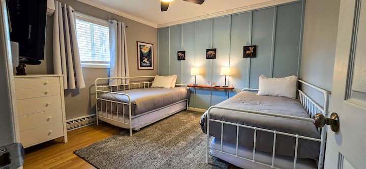 Guest Bedroom: Bright and inviting room with twin beds, trundles, forest-themed decor, and natural light!