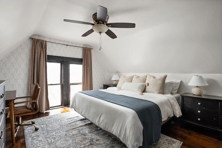 Ამ ოთახში წარმოდგენილია ფართო განლაგება დიდი ზომის საწოლით. Დიდი ფანჯარა დატბორავს სივრცეს ბუნებრივი სინათლით, ანათებს გლუვ ხის იატაკსა და მინიმალისტურ დეკორს. Საწოლთან მდგარ ორივე მაგიდაზე დგას დახვეწილი სანათები, ასევე, სამუშაო მაგიდა. 