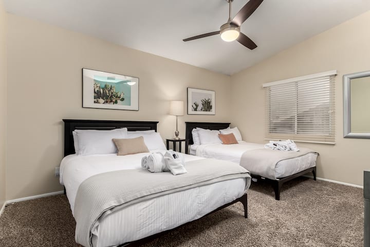 Пространа гостинска соба со два луксузни брачни кревета, уметнички дела од кактус и модерно осветлување - одлично за семејства или групи кои патуваат заедно.