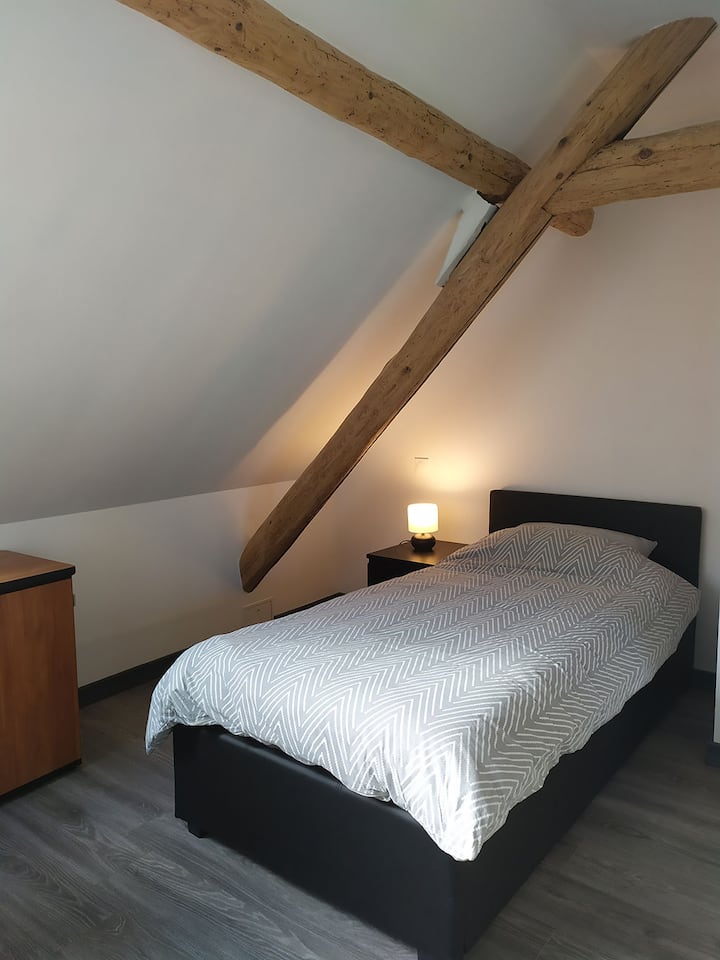 Spavaća soba od 13 m² ispod tavana s veluksom i sjenilom za zamračivanje, krevet 90 cm, veliki radni stol sa stolicom i foteljom,  malim namještajem za odlaganje i ormarom s ormarom.