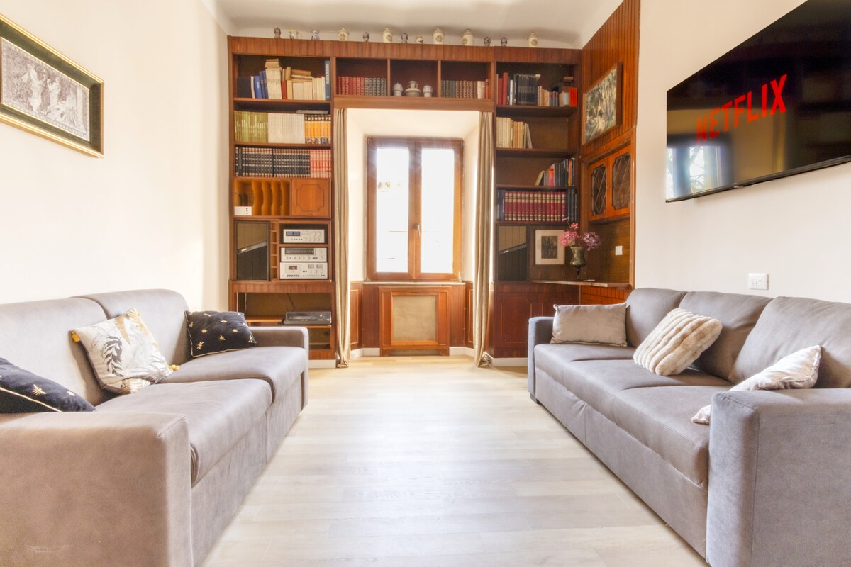 Útulná obývacia izba s rozkladacou pohovkou, knižnicou plnou kníh a inteligentným televízorom na zábavu.