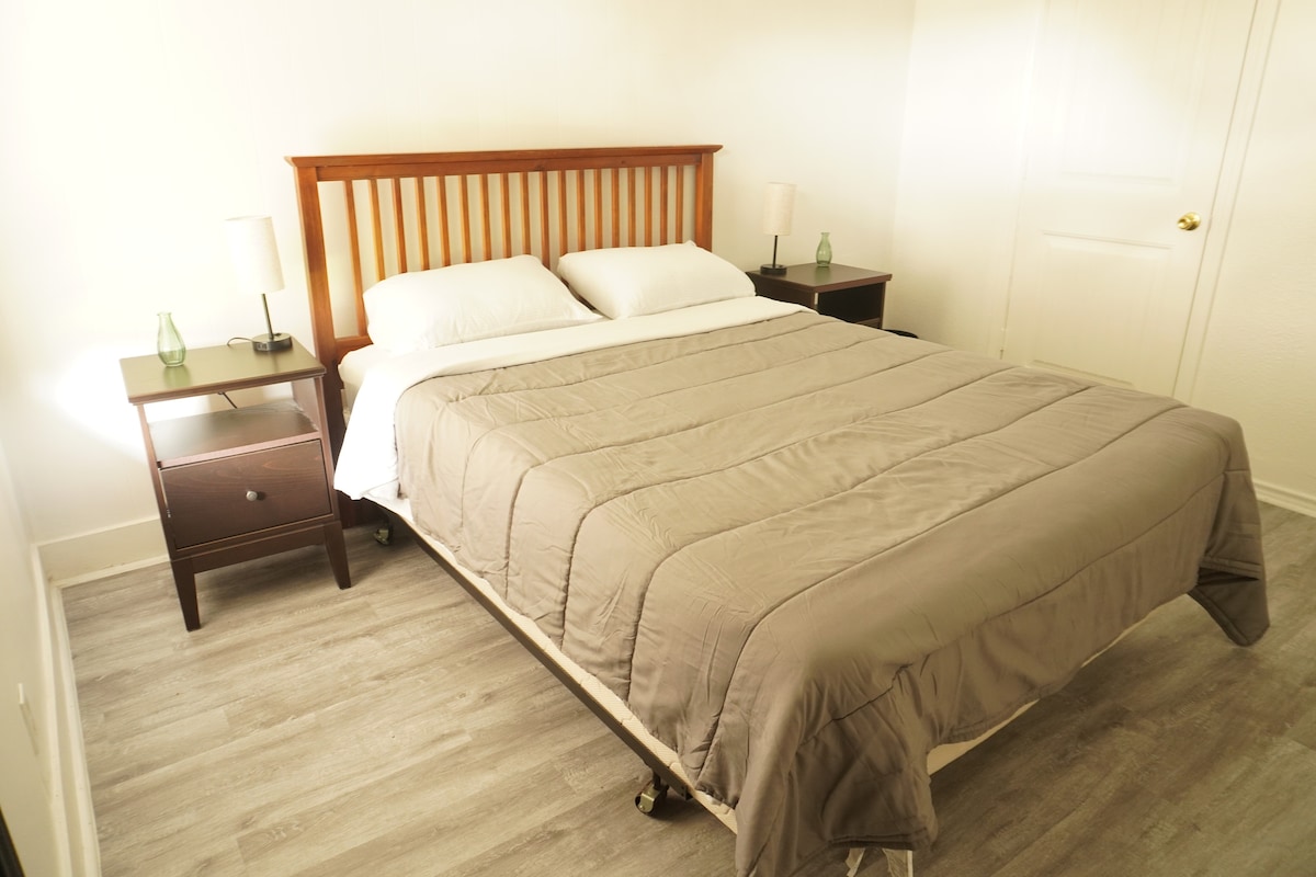 Este dormitorio cuidadosamente diseñado cuenta con una cama cómoda con tonos cálidos y neutros que crean un ambiente relajante. La clásica estructura de la cama de madera fue elegida para evocar una sensación de calidez y encanto atemporal, lo que hace que este espacio se sienta como un refugio sereno.