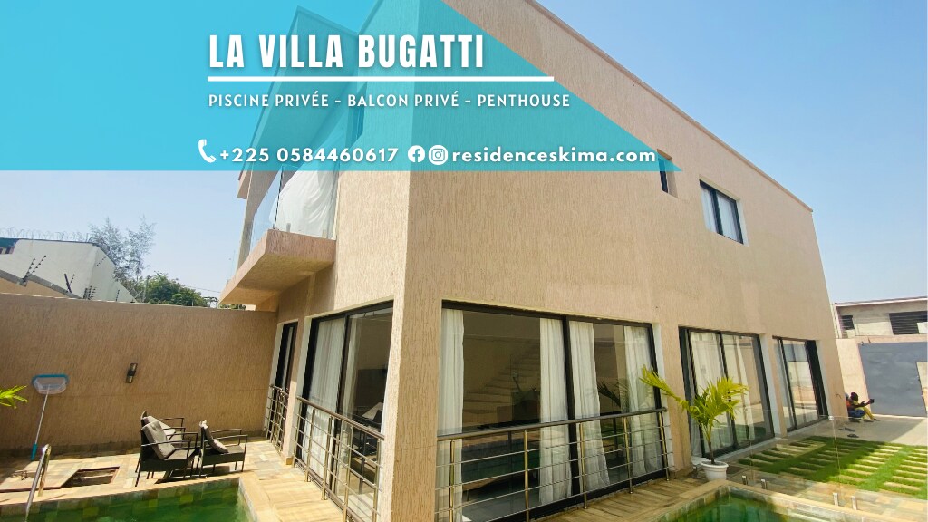 The photo showcases the exterior of a modern duplex structure, featuring large windows and a private pool. A balcony extends from the upper level, complementing the contemporary design. Lush greenery is visible around the pool area, adding a touch of nature to the setting.