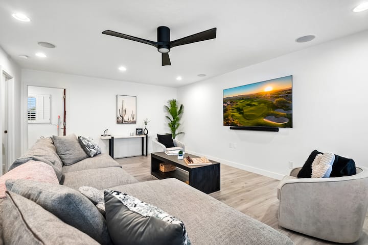 Amplia sala de estar con cómodos asientos, un amplio televisor y detalles modernos