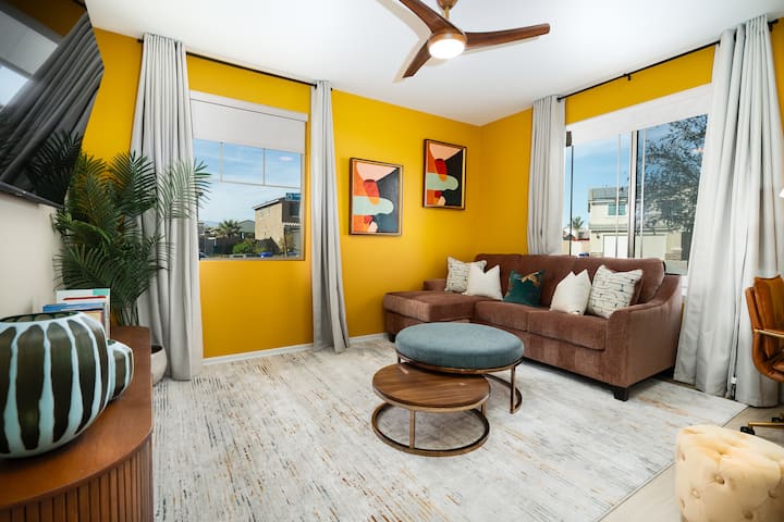 Sala de estar de entrada equipada con un sofá cama de tamaño completo, espacio de trabajo dedicado y TV inteligente