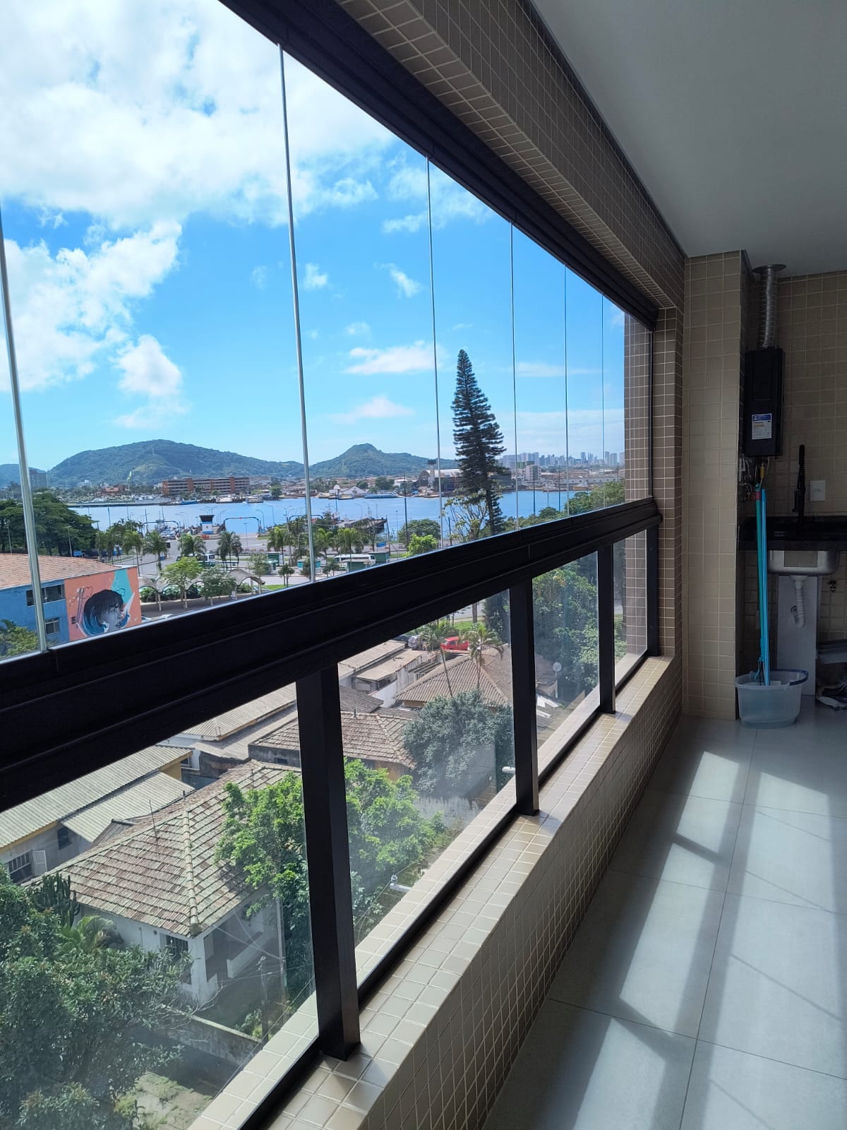 A spacious window offers expansive views of the sea and surrounding hills, allowing natural light to flood the area. The view captures the vibrant landscape, showcasing the harmony between the indoor and outdoor environments.