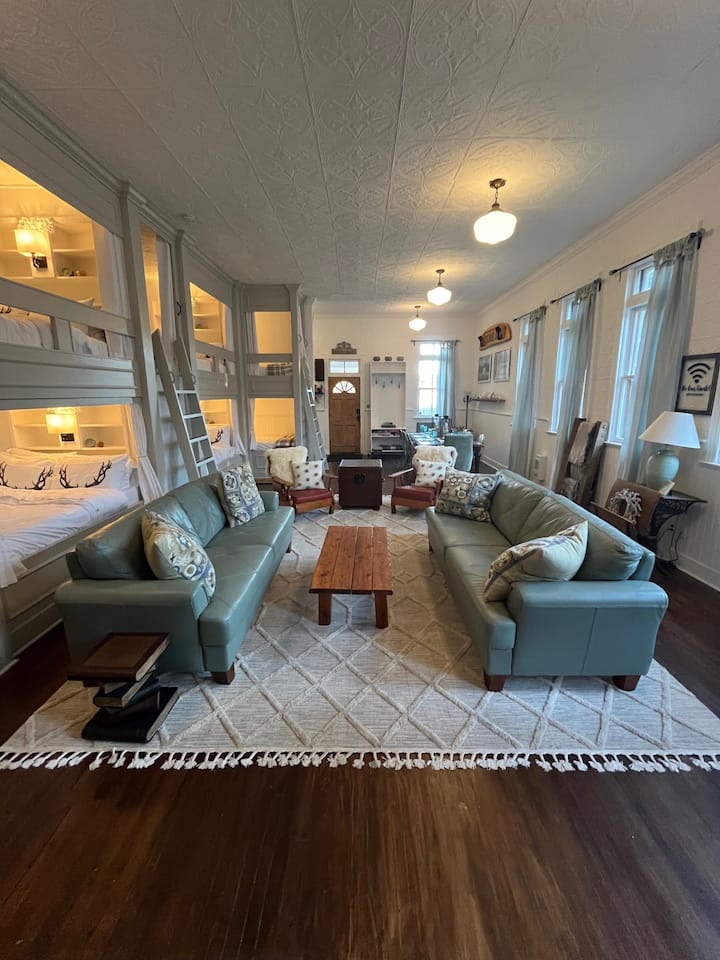 Chumba chetu Kikubwa kina madirisha makubwa nane, sakafu ya awali ya mbao ngumu na dari yenye nafasi ya futi kumi na mbili iliyofungwa na paneli ya awali ya bati. Kula, soma kitabu,  au pumzika tu mbele ya jiko letu la kuni. 