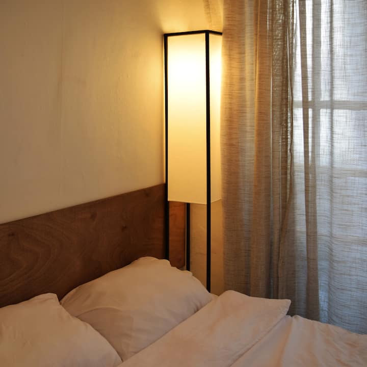 Hiki ni kitanda cha ukubwa wa malkia katika chumba cha kulala, kilicho tayari kukupa usingizi wa kupumzika wenye mwangaza wa joto na starehe.