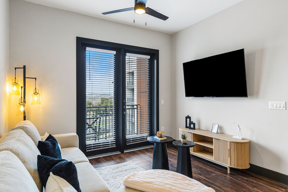 باب منزلق للوصول إلى الشرفة من غرفة المعيشة الحديثة هذه.