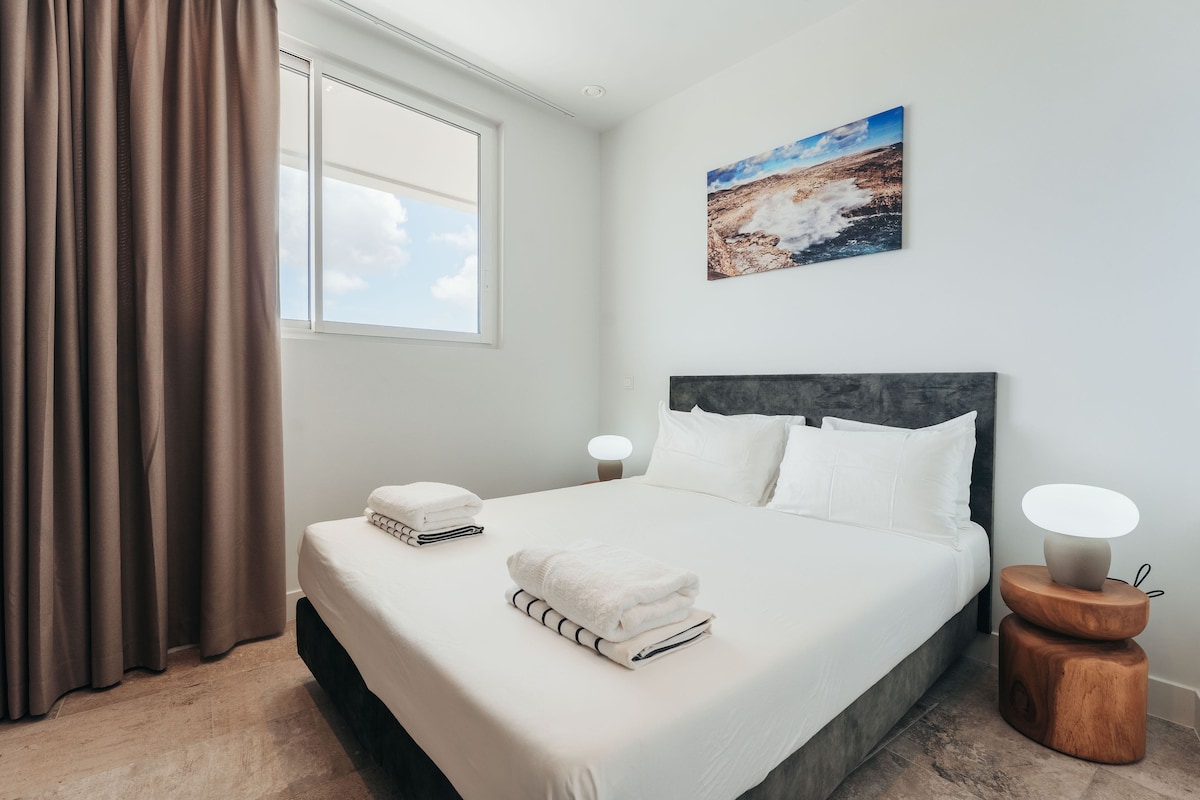 חדר השינה הנוח הזה כולל מיטת קינג-סייז עם מצעים נקיים, שידה מעץ מעוצבת עם מנורה ייחודית ויצירת אמנות יפה של נוף. תיהנו מאור טבעי ואווירה שלווה.