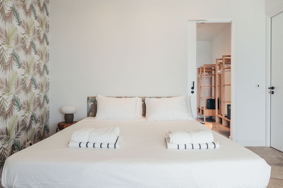 בחדר השינה הזה יש מיטת קינג סייז מרווחת עם מצעים נקיים ומגבות נקיות, עם טפט עלים של דקל. תיהנו מגישה נוחה לאזור הארונות לשהייה נוחה.