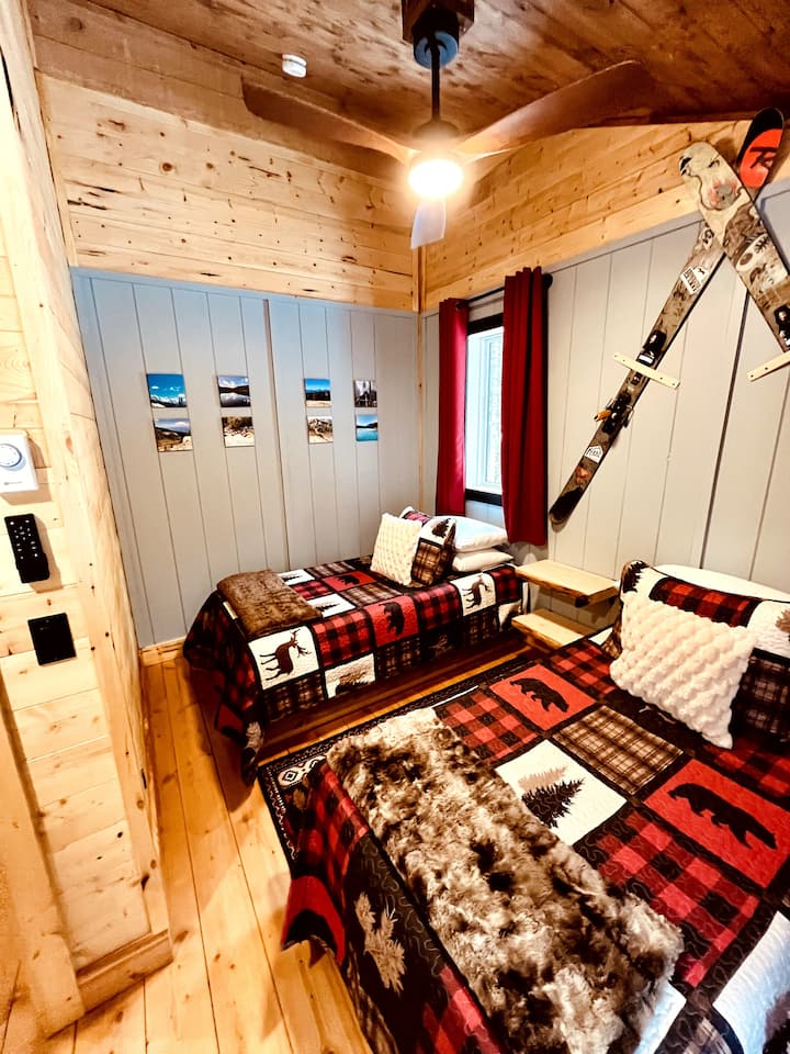 This cozy bedroom features two twin beds, vaulted ceilings, a ceiling fan for your comfort, and blackout curtains. It also includes children’s games & puzzles for added fun and entertainment, making it perfect for family stays.