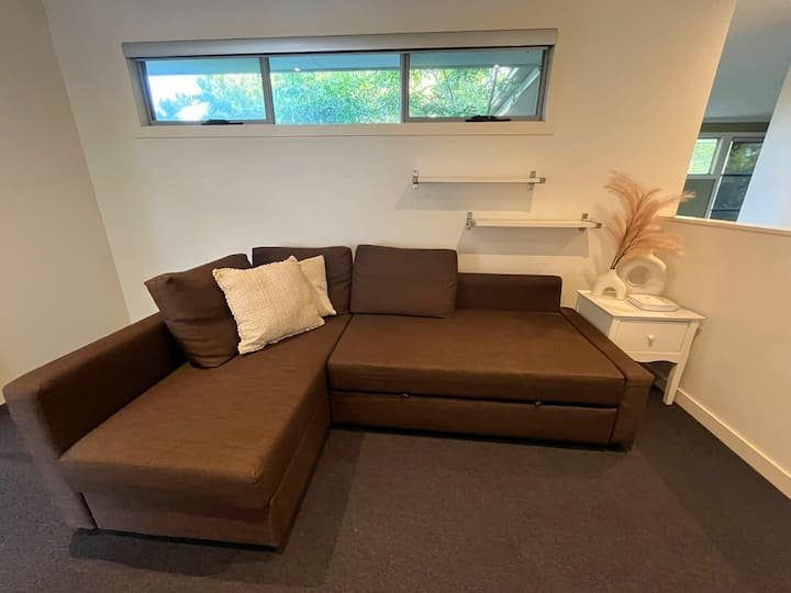 Fungua sehemu yenye zulia nje ya vyumba vya kulala iliyo na sofa ya kuvuta ambayo inalala 2. Inajumuisha dawati, ufikiaji wa bafu la pamoja na kabati lenye mito na mablanketi ya ziada kwa ajili ya kulala au mapumziko tulivu yanayoweza kubadilika.