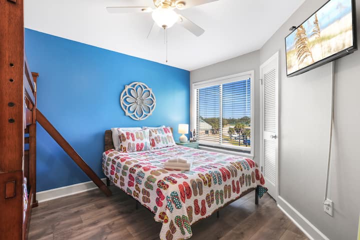 Rest easy in this cheerful bedroom where colorful coastal touches and sunlight create a happy retreat.