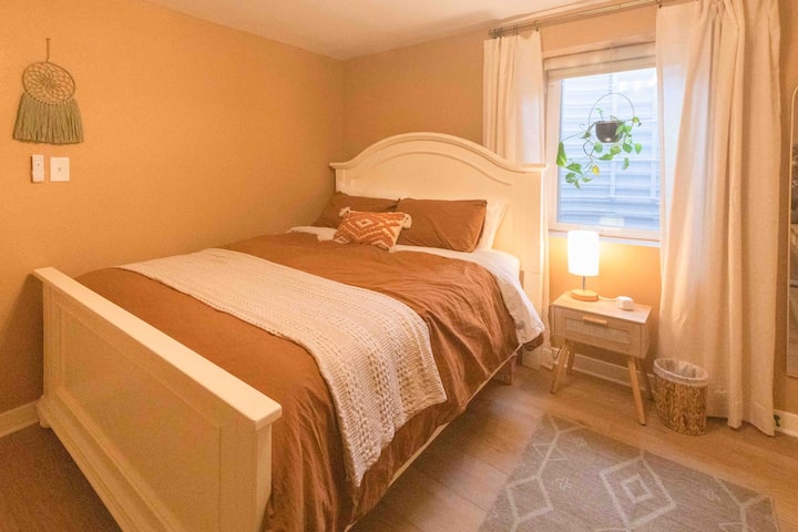 El dormitorio 1 cuenta con una cómoda cama tamaño queen, ventilador de techo, ventanas de salida equipadas con persianas oscuras, una mesita de noche con una lámpara táctil, un puerto de carga adaptable y máquinas de ruido blanco. 