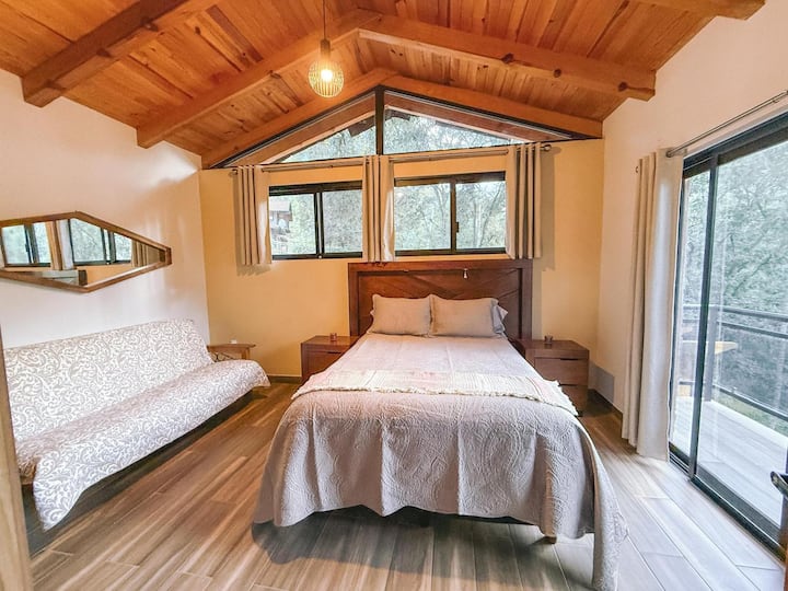 Chumba kikuu cha kulala chenye kitanda kikubwa na kitanda cha sofa.

Madirisha mapana hukuruhusu kuungana na mazingira ya asili na kufurahia mandhari nzuri.
