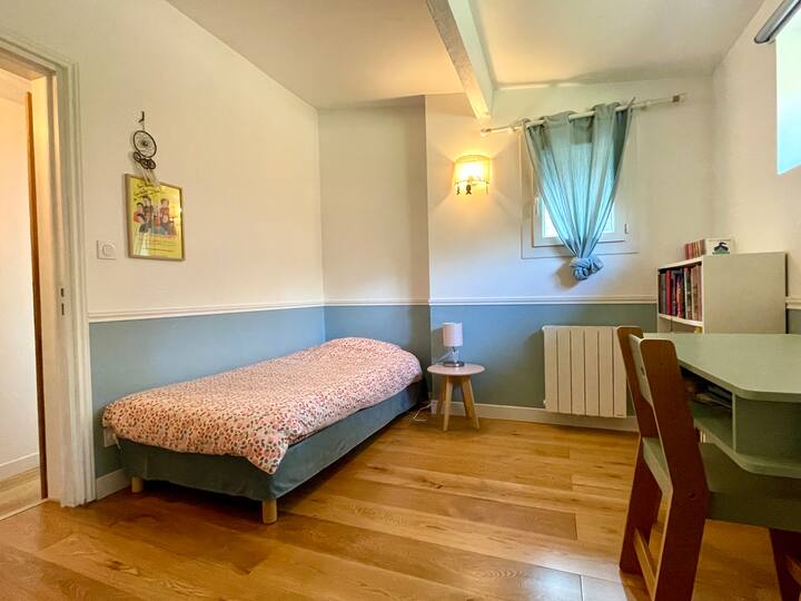 ห้องนอนพร้อมเตียงเดี่ยว (90 x 190 ซม.) หน้าต่าง 2 บานมองเห็นต้นไม้ด้านหลังบ้าน