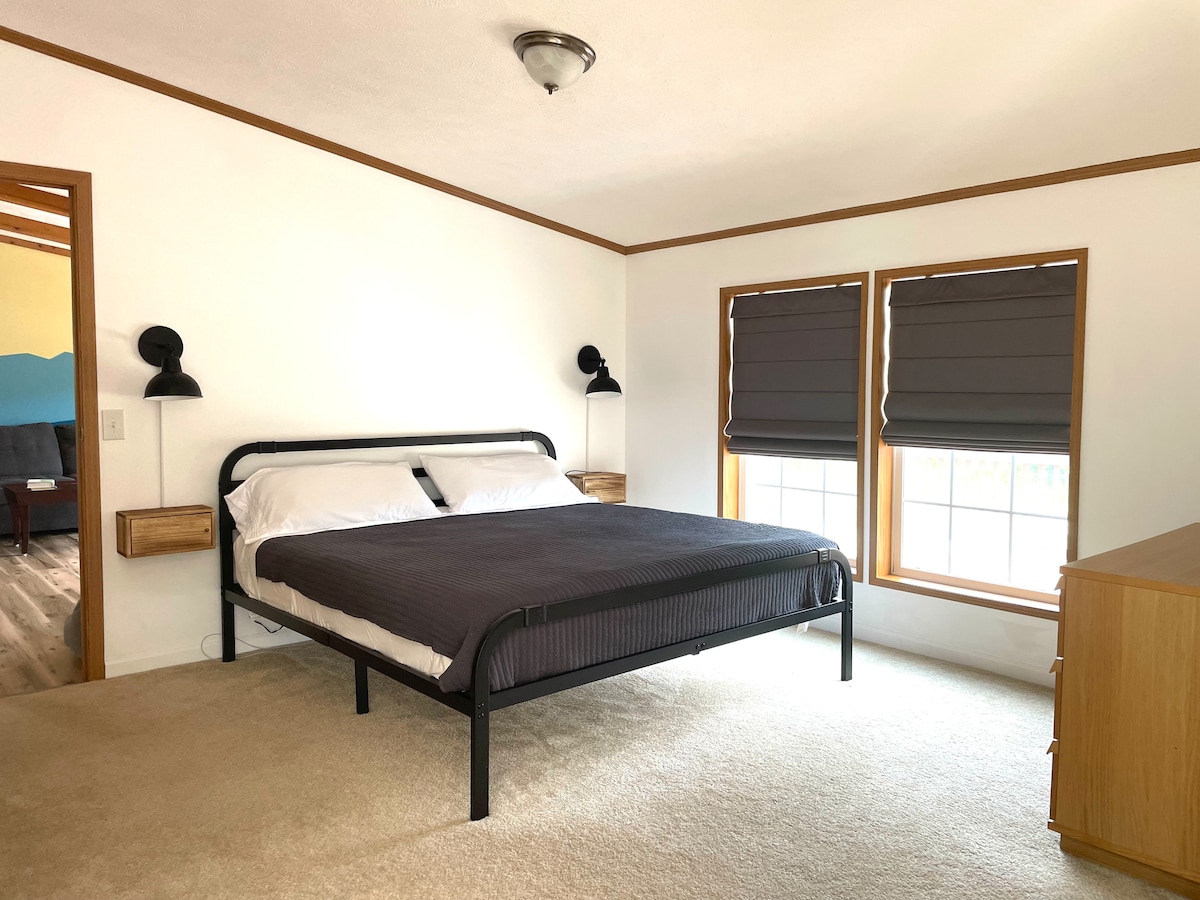 Kingsize bed met dressoir, raam met uitzicht op de vallei.  Slaapkamer 1 heeft ook een eigen badkamer ("Badkamer 1") en zithoek met bank en tv.