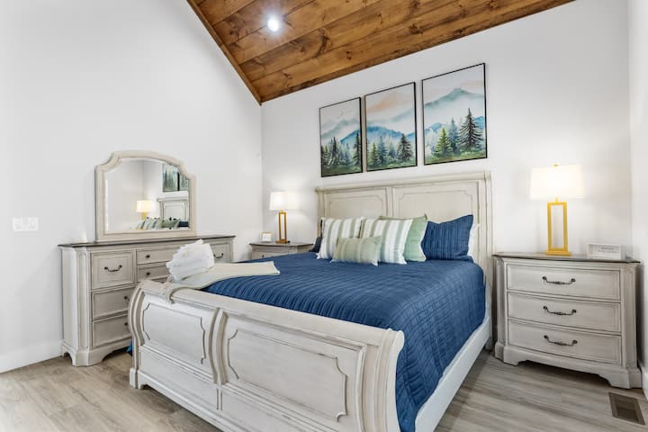 Spavaća soba ima dva noćna ormarića i komodu s ogledalom