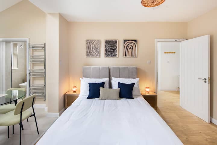 Spacious studio with a zip-link double bed, dining area, workstation, ensuite bathroom, and a small kitchen featuring a microwave, toaster, kettle, oven, and top burner with an exhaust fan. Includes a washer and dryer for added convenience.