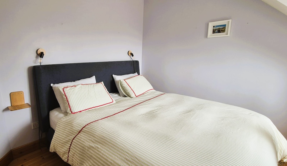 这间客卧配备一张非常舒适的超大双人床。 它还被设置为家庭办公空间，配有大屏幕和打印机。