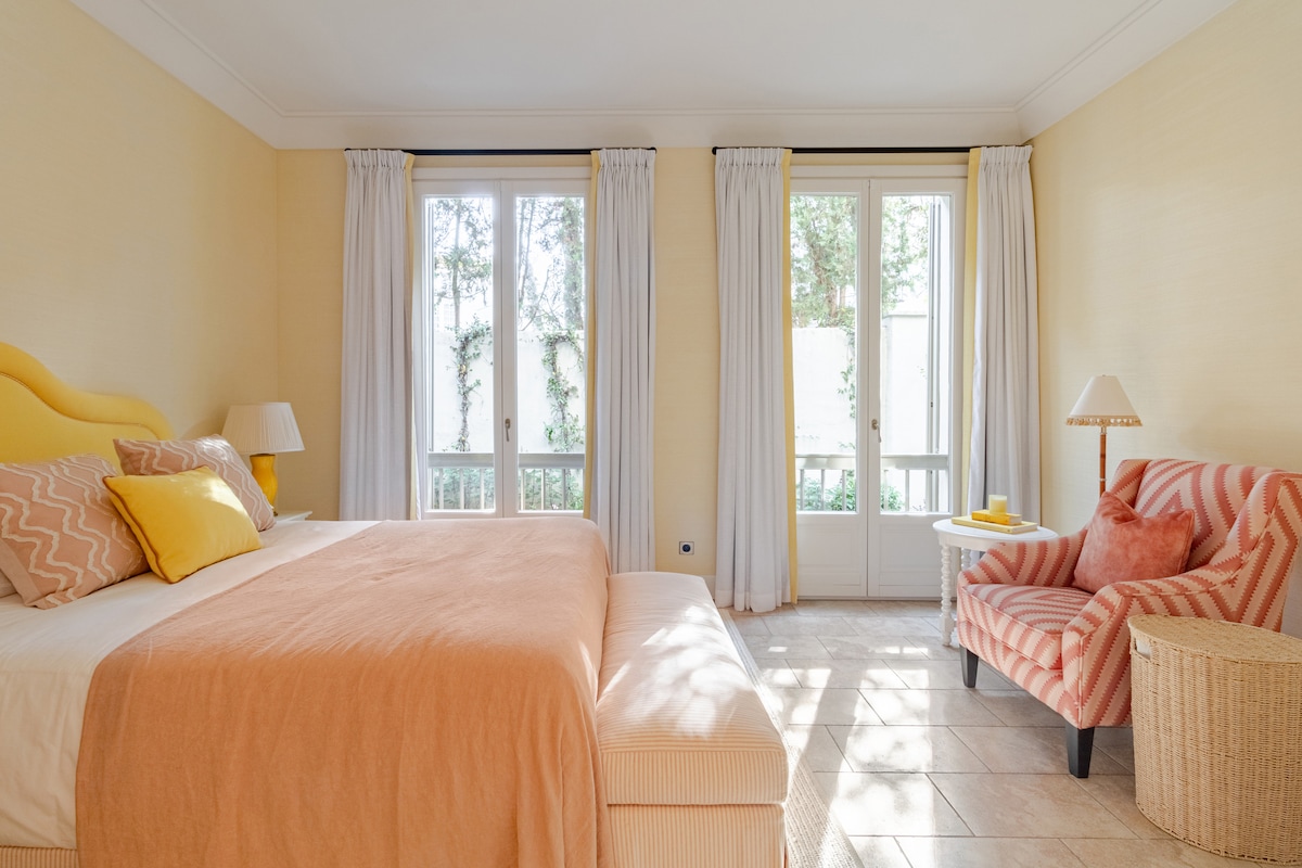 Charming and light-filled double bedroom with elegant décor, large French windows, and calming neutral tones located on the ground floor. Features a comfortable double bed, soft seating, and beautiful built-in storage for a relaxed and restful stay.