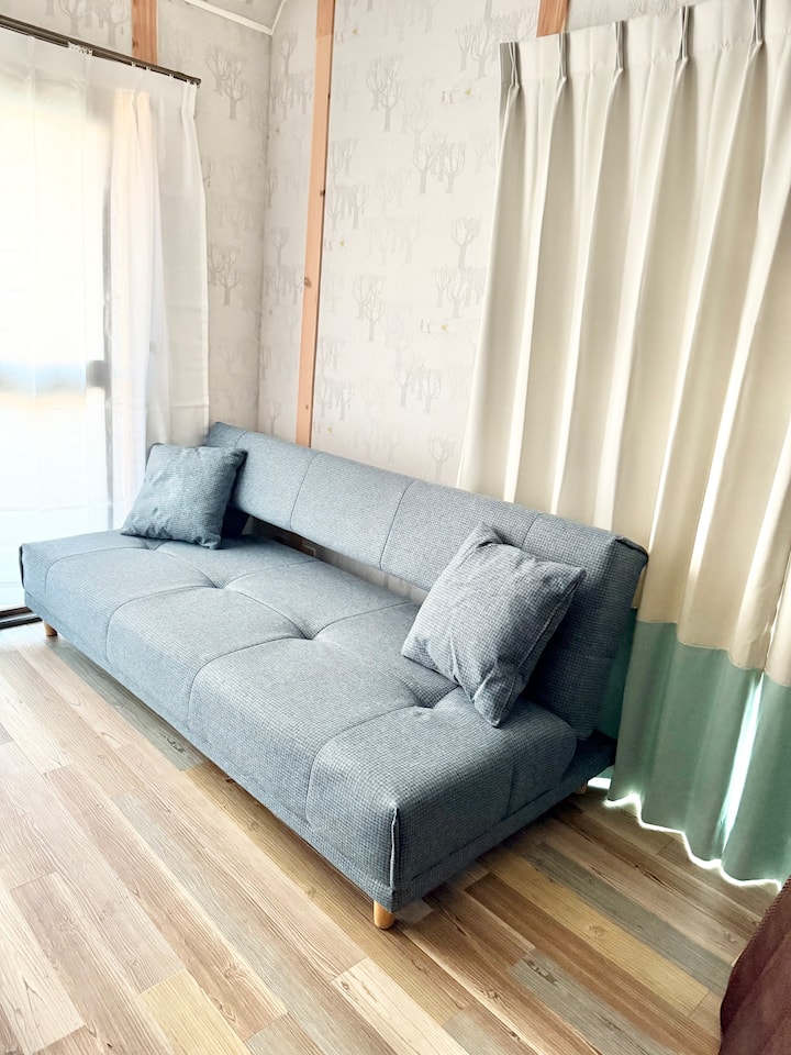 ספה נפתחת בסלון.יש שניים כדי ששני אנשים יוכלו לישון.
אם אתם 4 אנשים או פחות, אתם יכולים להירגע כמו ספה.
בסלון יש מסך גדול, כך שתוכלו לצפות באינטרנט כמו ביוטיוב על מקרן התקרה.
כמו כן, יש מרפסת גדולה מסביב לחדר.
כשאתם יוצאים למרפסת, יש ספסל ייחודי שעשוי מעץ סחף, ואתם יכולים לראות את גורדי השחקים סביב תחנת נגויה.