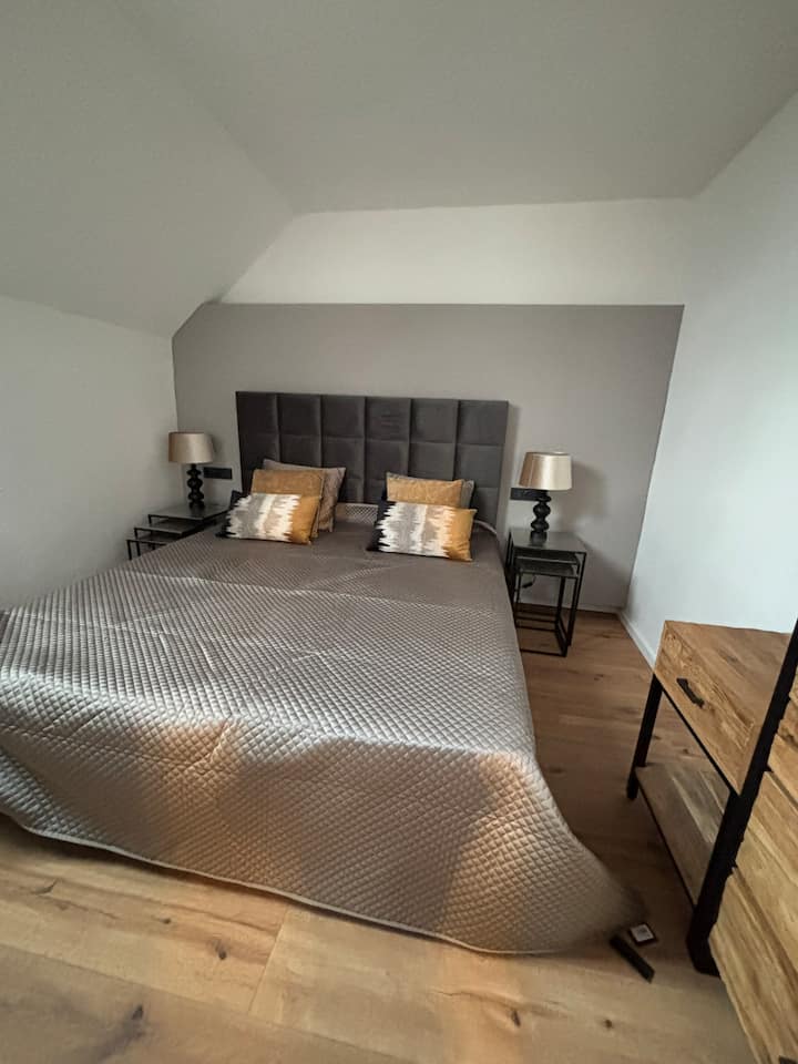 El dormitorio ofrece la máxima comodidad con una amplia cama de somier (180 cm de ancho) y edredones de gran tamaño. La luz se puede apagar directamente desde la cama. Además, los enchufes están equipados con conexiones USB y USB-C.