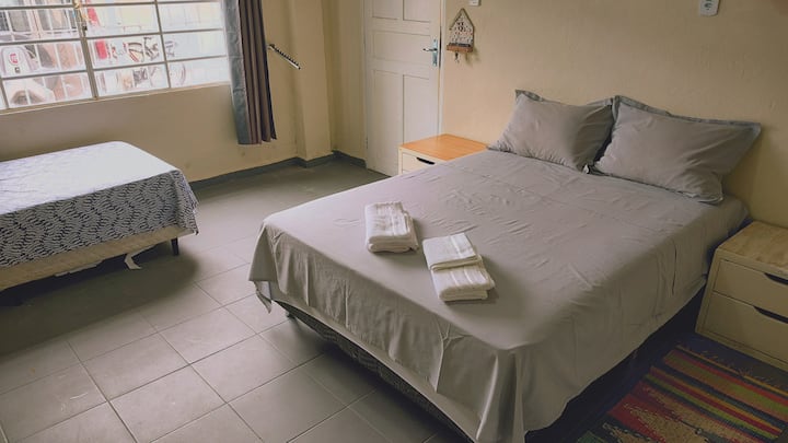 Dormitorio con cama doble, cama individual y mesita de noche.