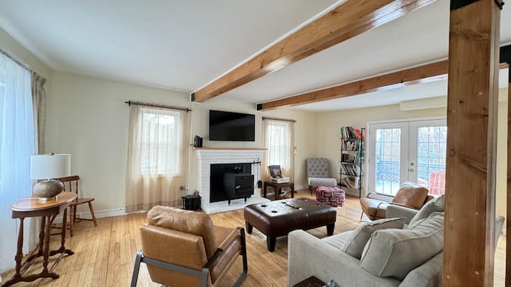 Casa #2: Encantadora sala de estar con una estufa a leña y elegantes puertas francesas dobles que conducen a una serena terraza en el patio trasero.