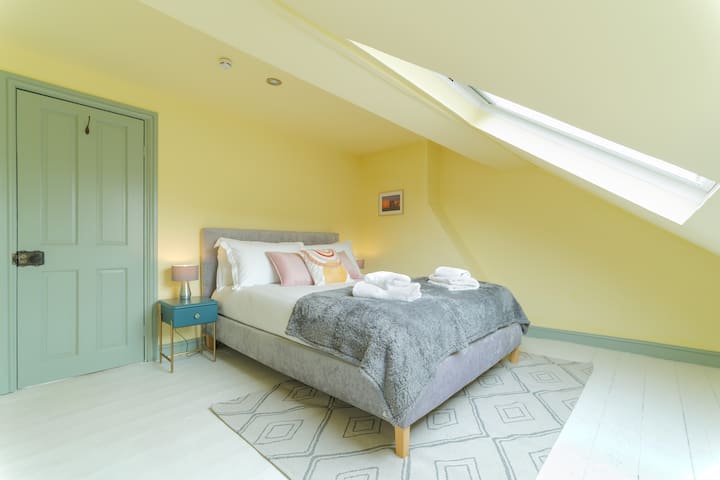 Top floor bedroom with super comfy King Size bed, bedside lamps, clothes hanging rail and luggage stand.