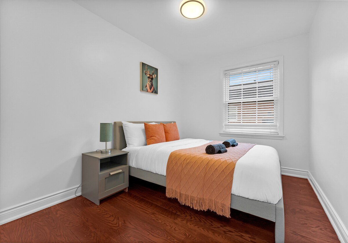 Ნათელი და სტუმართმოყვარე დედოფლის საძინებელი თამამი ნარინჯისფერი აქცენტებითა და რბილი ბუნებრივი განათებით.

