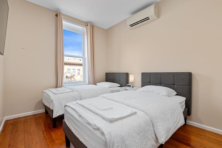 Dormitorio luminoso y aireado con dos camas individuales, un televisor inteligente grande y mucha luz natural. Ideal para niños, amigos o huéspedes adicionales.