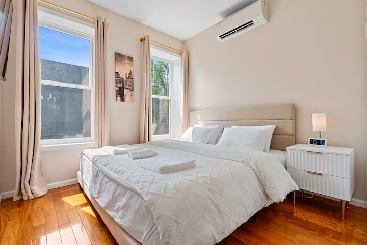 Dormitorio principal con una cama tamaño king, un televisor inteligente grande y mucha luz natural. Cuenta con un amplio armario colgante y una cerradura en la puerta para mayor privacidad.