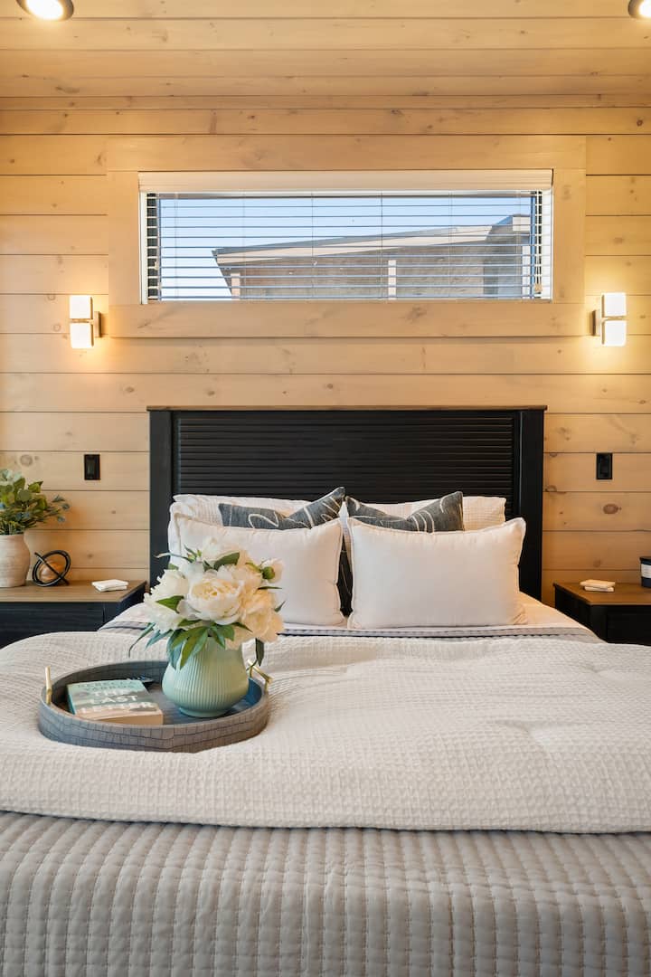This bedroom features a cozy queen bed upgraded with a plush foam topper for added comfort. A floor-length mirror adds a touch of style and function, while soft textures and thoughtful details create a luxurious, restful space. Located upstairs.