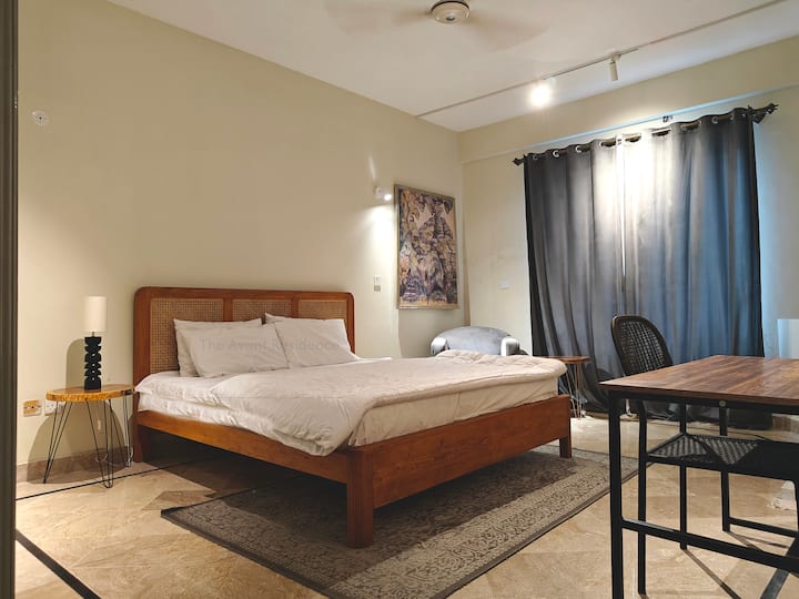 Un moderno letto king-size con una testiera in rattan tradizionale, lampade personalizzate che si adattano al contesto, una scrivania per lavorare comodamente. 