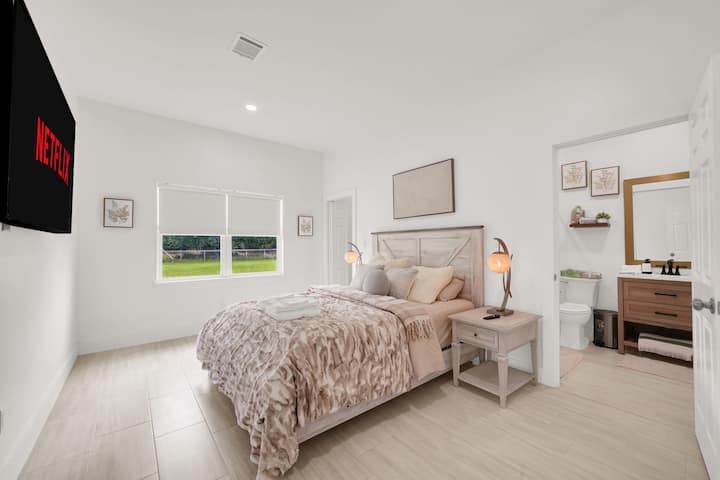 Relax in this bright, modern bedroom featuring a private ensuite bathroom and a large screen for your favorite movie nights.