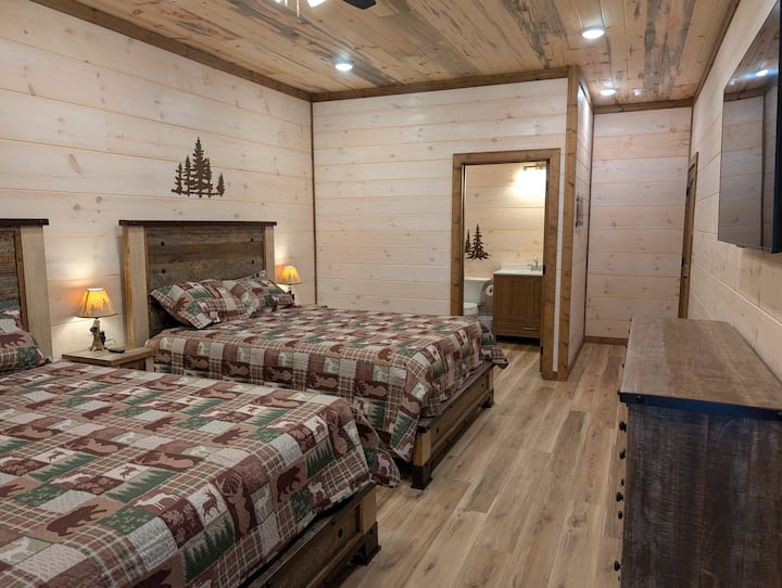 למטה מיטות זוגיות קווין סייז עם חדר רחצה צמוד וטלוויזיה חכמה 55 אינץ'.