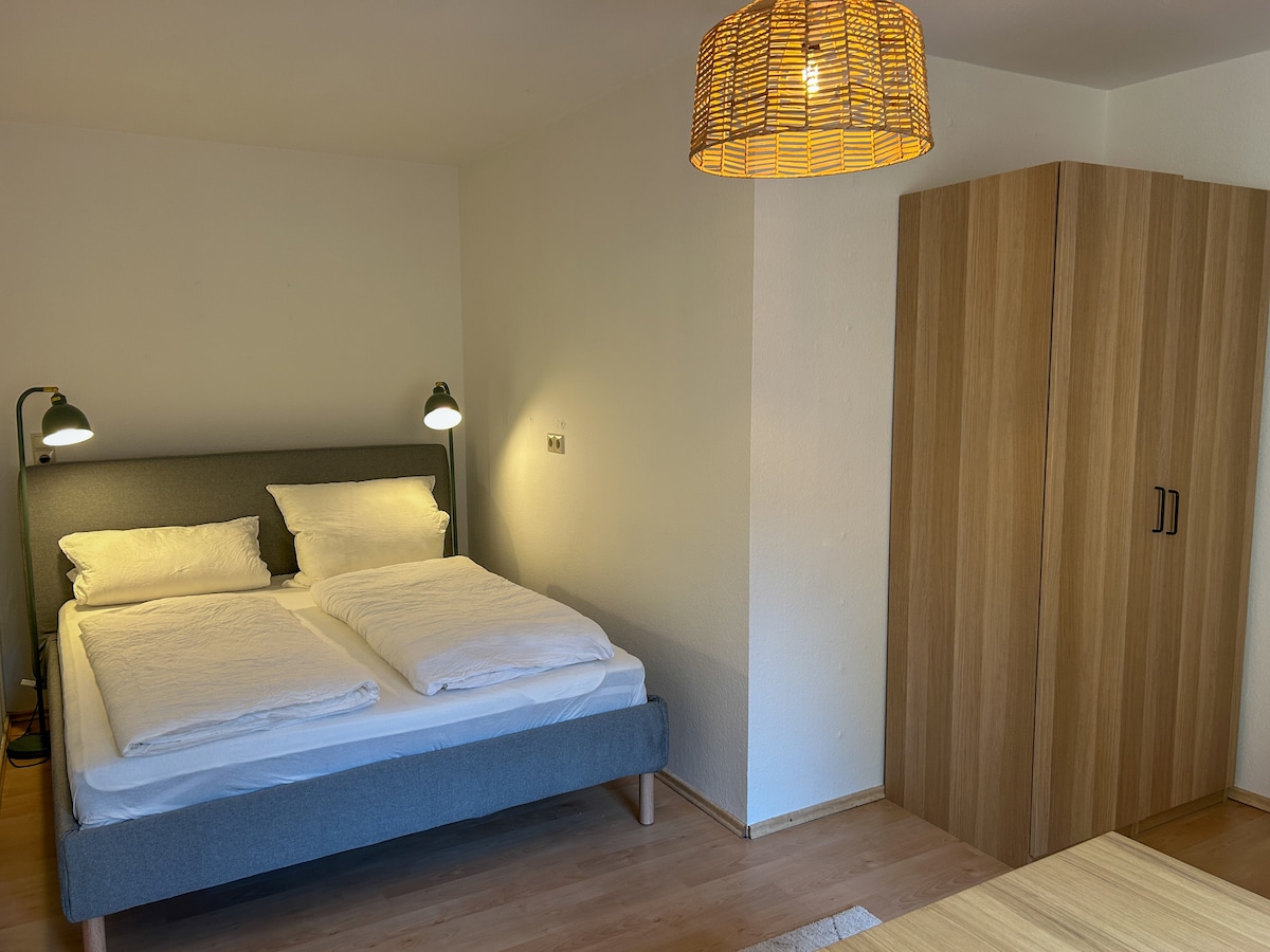 Habitación compacta con una cómoda cama de matrimonio (1,60 × 2,00 m), ideal para parejas o personas que viajan solas. Las líneas claras, la luz cálida y un ambiente acogedor garantizan una noche de sueño relajante.