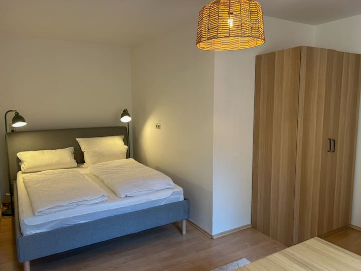 Kompaktes Schlafzimmer mit bequemem Queen-Size-Bett (1,60 × 2,00 m), ideal für Paare oder Alleinreisende. Klare Linien, warmes Licht und gemütliches Ambiente sorgen für eine entspannte Nachtruhe.